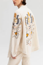 Off-white kimono jacket with embroidery in dusty pastel colors.